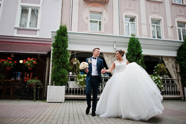 Recién casados caminando por la calle de un casco antiguo con cafetería y flo — Foto de Stock