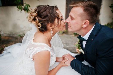 Ivy ile eski duvar yanında oturan muhteşem Düğün çifti bir