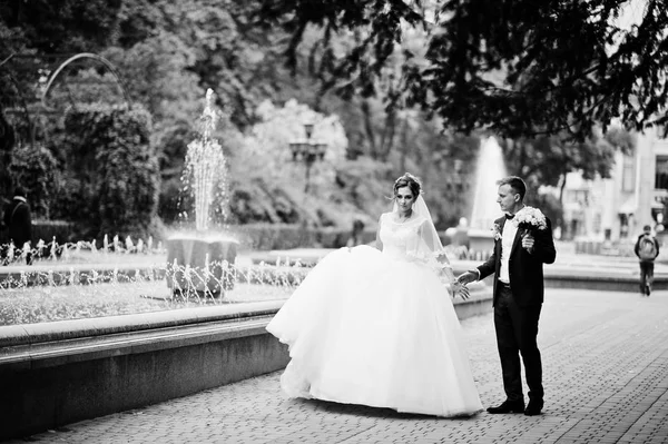 Couple de mariage marche et sourire sur le trottoir avec une fontaine i — Photo
