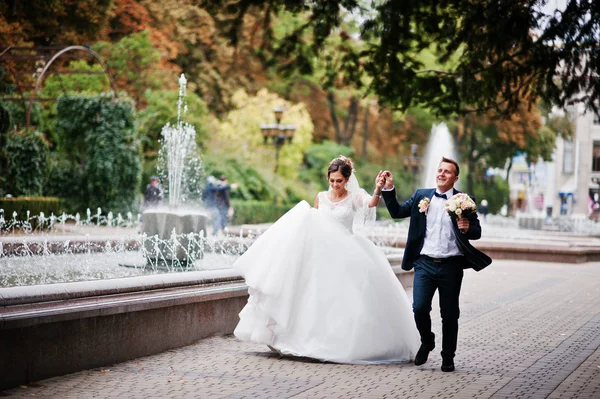 Ślub para spaceru i uśmiecha się na bruk z fontanną i — Zdjęcie stockowe