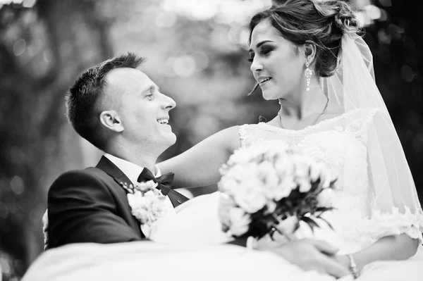 Excelente noiva sentada no colo do marido durante o casamento — Fotografia de Stock