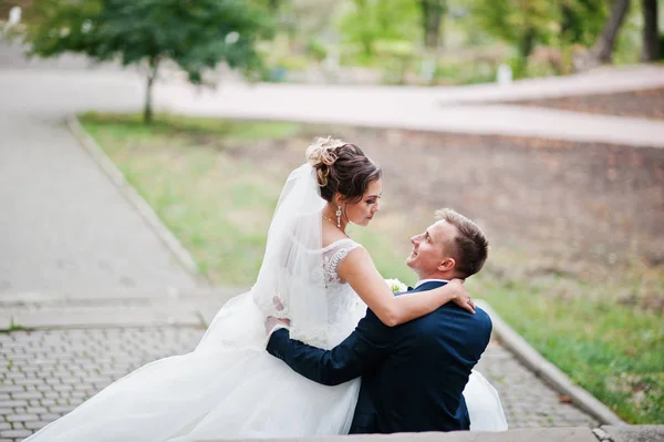 Outstanding bride sitting on her husband's lap during their wedd — Stock Photo, Image