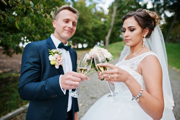 幸せな新婚夫婦、ウェディング ブーケに公園で屋外のシャンパンを飲む — ストック写真