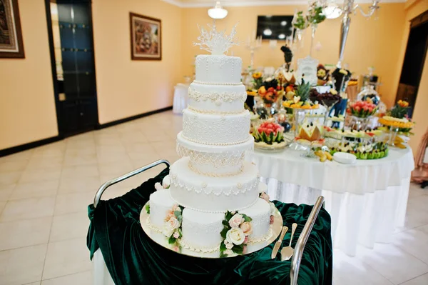 Niesamowite i pyszne beżowy tort weselny stojący na stole i — Zdjęcie stockowe
