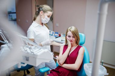 Diş ağrısı için bekleyen bir diş sandalyede oturan üzgün hastayla