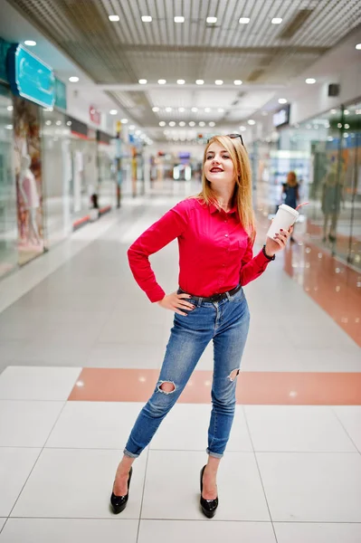 Portrait of a gorgeous woman in red blouse and jeans holding a c