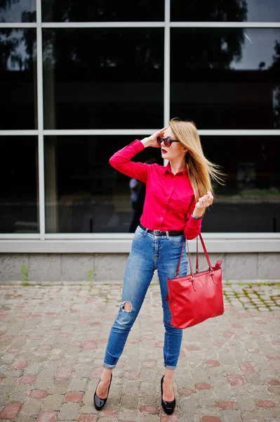 Portrait of a fabulous young woman in red blouse and jeans posin