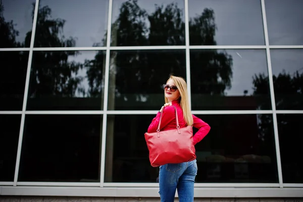 Portrait of a fabulous young woman in red blouse and jeans posin