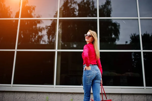 Portret van een prachtige jonge vrouw in rode blouse en jeans posin — Stockfoto