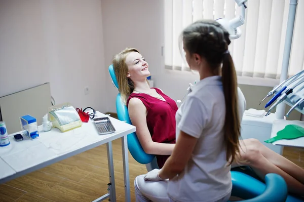 Attraktive Patientin im rot-violetten Kleid auf dem Zahnchai liegend — Stockfoto