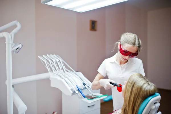 Dentista feminina em óculos vermelhos especiais tratando o tee de sua paciente — Fotografia de Stock