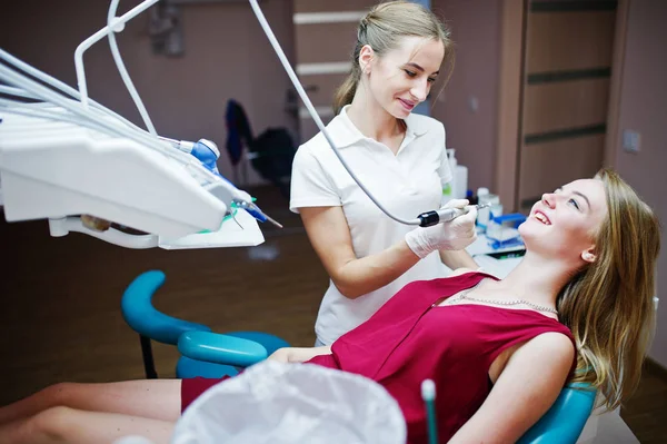Aantrekkelijke patiënt in rood-violet jurk opleggen aan de tandheelkundige chai — Stockfoto