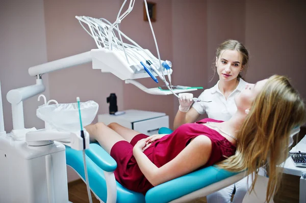 Attraktiva patienten i röd-violett klänning handpåläggning den dentala chai — Stockfoto
