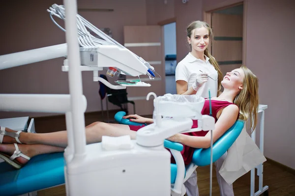 Attraktiva patienten i röd-violett klänning handpåläggning den dentala chai — Stockfoto