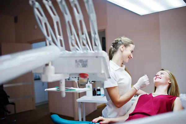 Attraktive Patientin im rot-violetten Kleid auf dem Zahnchai liegend — Stockfoto