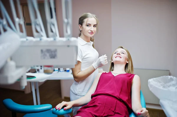 Attractive patient in red-violet dress laying on the dental chai