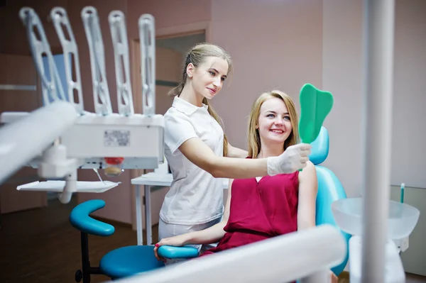 Bella dentista mostrando i nuovi denti del suo paziente attraverso il mi — Foto Stock