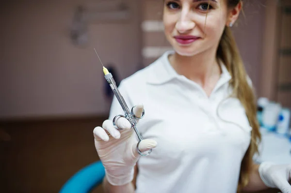 Portrait of a female dentist in white coat posing with syringe f — Stock Photo, Image