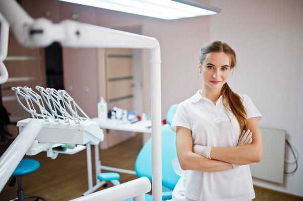 Good-looking female dentist posing in white coat in a modern wel