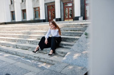 Yakışıklı genç kadın beyaz bluz, geniş siyah pantolon ve b