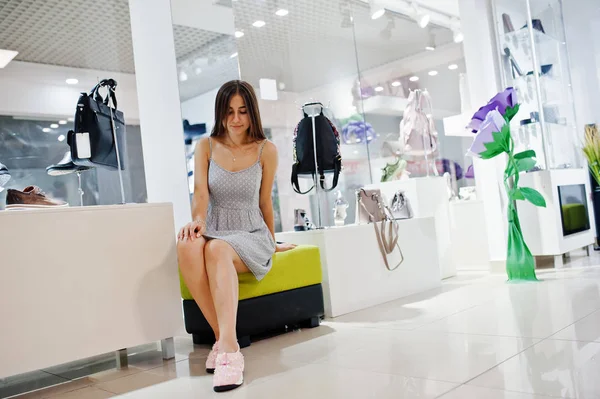 Jeune femme étonnante essayer des chaussures de sport dans la boutique tout en étant assis — Photo