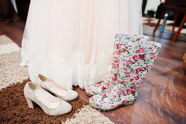 Foto de cerca de los tacones altos de la novia y botas de goma con flora — Foto de Stock