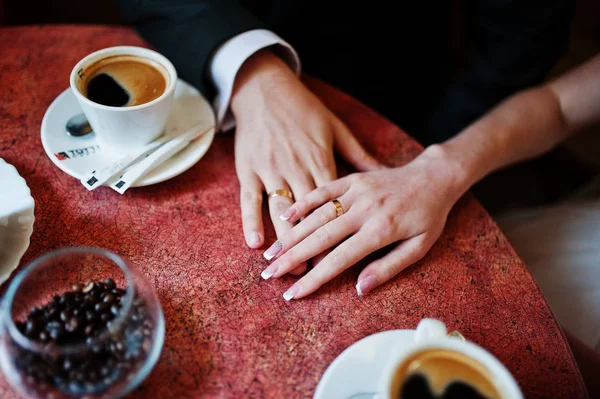 Foto de cerca de una pareja de novios tomados de la mano en un pequeño café — Foto de Stock