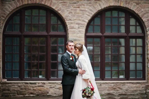 Fabelhaftes Hochzeitspaar beim Spazierengehen und Posieren neben dem alten Gebäude — Stockfoto