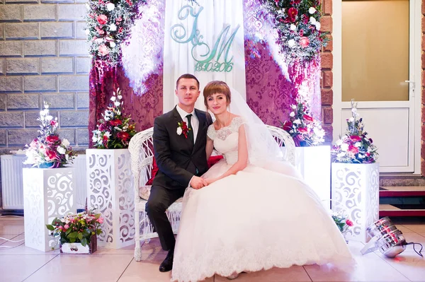 Increíble pareja de boda posando bajo el arco decorado con flo — Foto de Stock