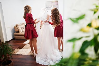 Nedime gelin gelinlik üzerinde bir yay bağlamak yardım.