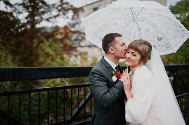 Yağmurlu bir günde yürüyüşe bir şemsiye ile çift düğün.