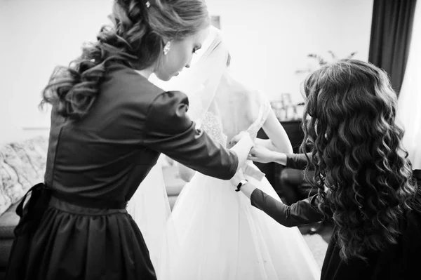 Bridesmaids helping bride to tie a bow on a wedding dress. Black — Stock Photo, Image