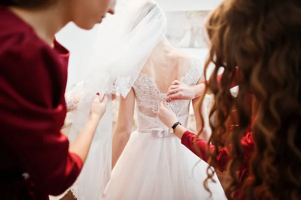 Koszorúslányok segít lekötni egy íj, egy esküvői ruha a menyasszony. — Stock Fotó