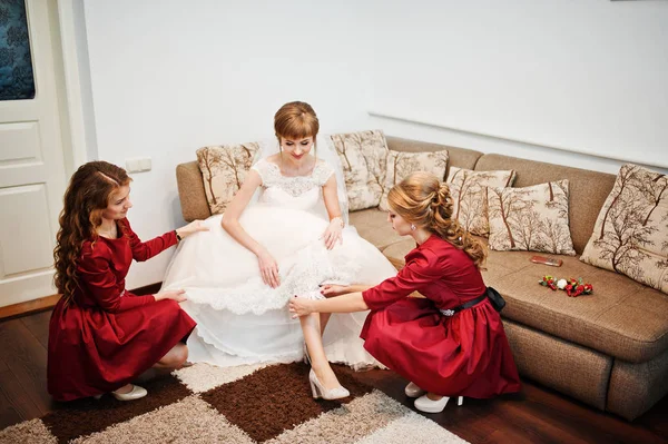 Damas de honor ayudando a la novia a poner una liga para la boda . — Foto de Stock