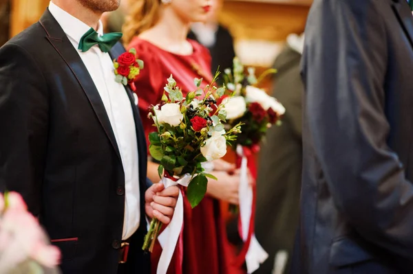Close-up photo of groomsman and bridesmaid holding small bouquet — Stock Photo, Image
