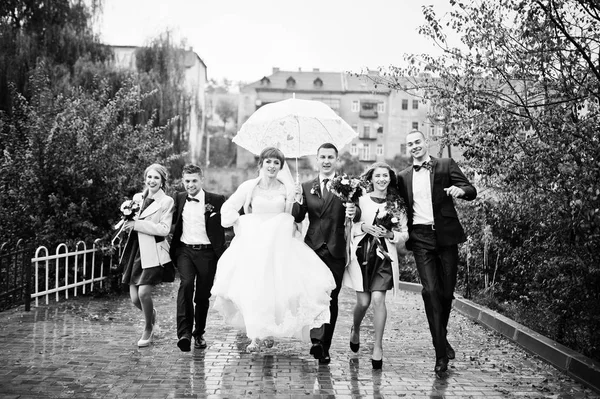 Casamento casal e padrinhos com damas de honra andando em uma chuva — Fotografia de Stock