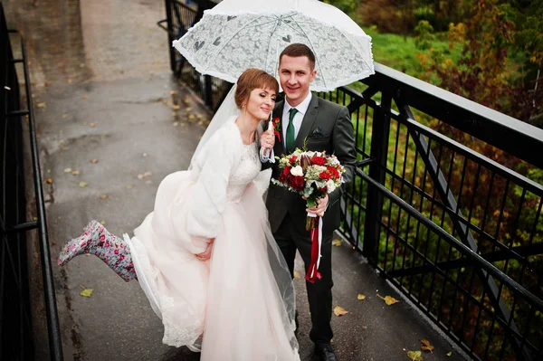 Casamento casal dando um passeio com um guarda-chuva em um dia chuvoso . — Fotografia de Stock