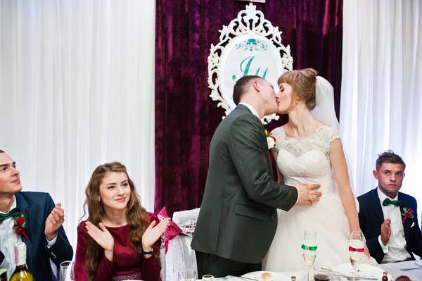 Pareja de boda besándose en la mesa en el restaurante . — Foto de Stock