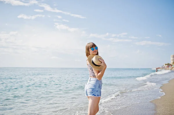 Hermosa modelo relajante en una playa de mar, vistiendo en jeans sho —  Fotos de Stock