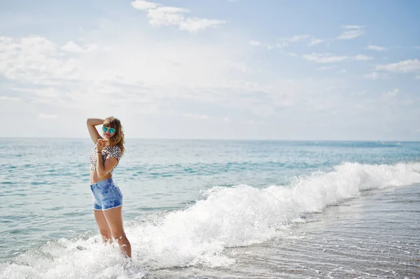 Το όμορφο μοντέλο χαλαρώνοντας σε μια παραλία της θάλασσας, φορώντας την τζιν sho — Φωτογραφία Αρχείου