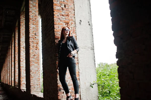 Fille élégante aux cheveux rouges en lunettes de soleil porter en noir, contre aba — Photo