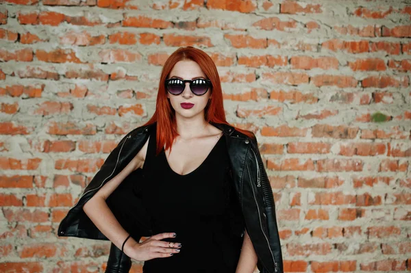 Menina de cabelo vermelho elegante em óculos de sol desgaste em preto, contra aba — Fotografia de Stock
