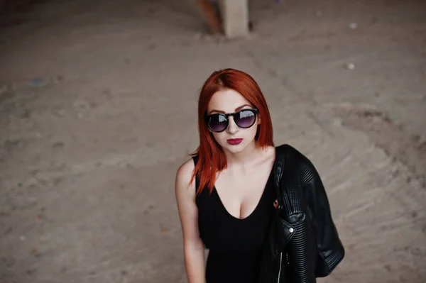 Red haired stylish girl in sunglasses wear in black, against aba — Stock Photo, Image