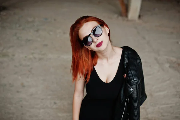 Menina de cabelo vermelho elegante em óculos de sol desgaste em preto, contra aba — Fotografia de Stock