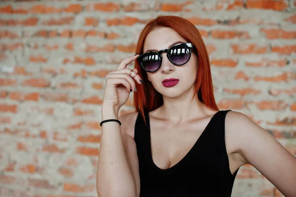 Рыжеволосая стильная девушка в солнечных очках одевается в черное, против Абы — стоковое фото