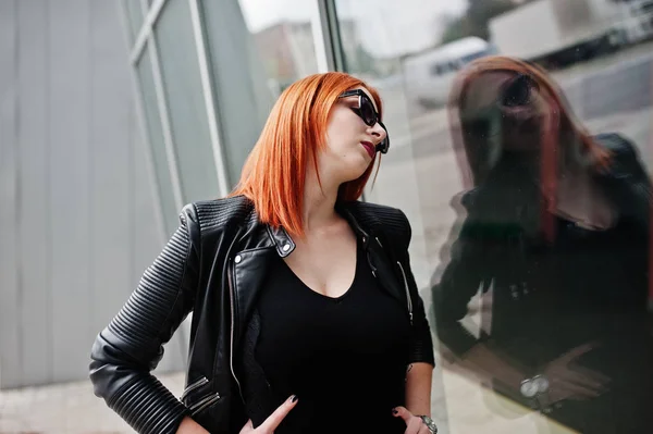 Menina elegante de cabelos vermelhos em óculos de sol desgaste em preto, contra o lar — Fotografia de Stock