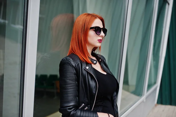 Röd haired snygg tjej i solglasögon slitage i svart, mot lar — Stockfoto