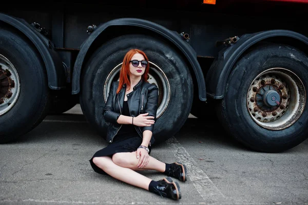 Червоне волосся стильна дівчина в чорному, сидить на тлі великої вантажівки — стокове фото