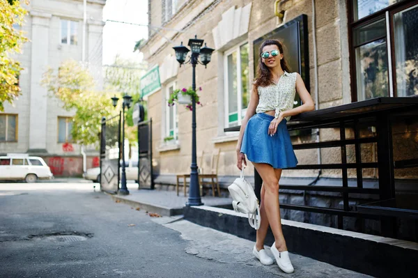 Lockiges stylisches Mädchen trägt blauen Jeansrock, Bluse und Sonnenbrille — Stockfoto