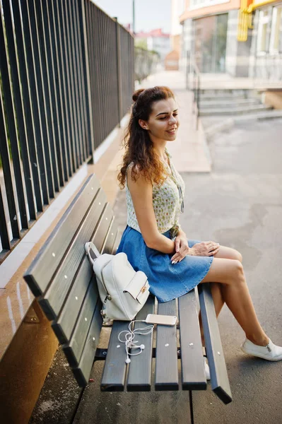 Lockigt snygg tjej slitage på blå jeans kjol, blus sitter på b — Stockfoto